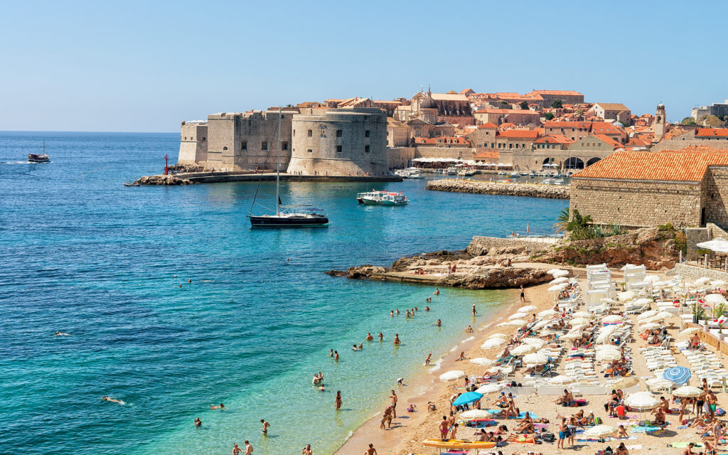 Dubrovnik, Croatia - August 20, 2016: People on beach and Dubrovnik fortress in Adriatic Sea, Croatia